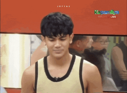 a man in a yellow tank top is standing in front of a red wall that says kapamilya