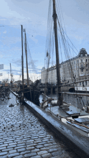 a row of boats are docked in a harbor on a cobblestone street