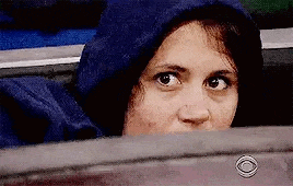 a woman in a blue hoodie is sitting in a car looking out the window .