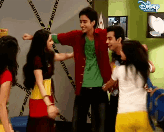 a group of people are dancing in front of a disney channel wall