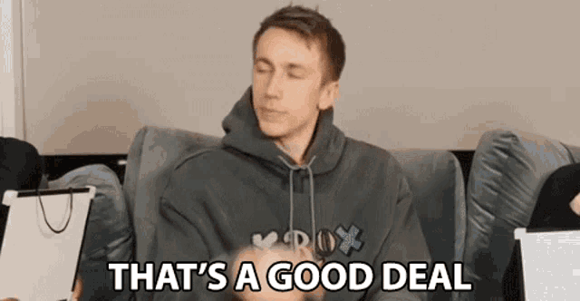 a man in a hoodie is sitting on a couch with his eyes closed and saying `` that 's a good deal ''