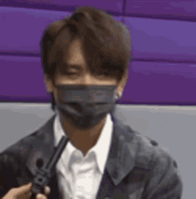 a man wearing a face mask is being interviewed by a person holding a microphone .