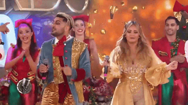 a group of people are dancing on a stage while a man holds a microphone .