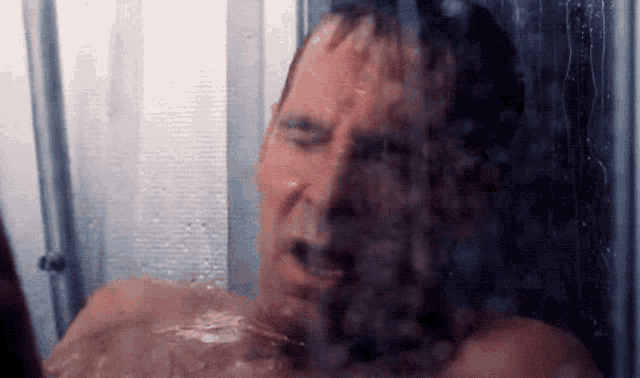 a man is taking a shower with his eyes closed and his mouth open