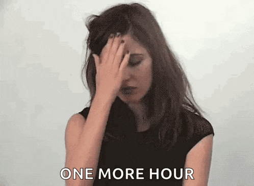 a woman is covering her face with her hand and the words `` one more hour '' are behind her .