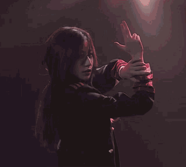 a woman in a black jacket is dancing on a stage with her hands in the air .