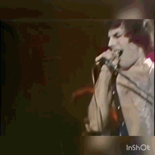 a man is singing into a microphone while holding a stick in his mouth .
