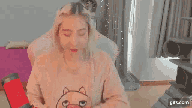 a woman is sitting in a chair wearing a pink pig sweater .
