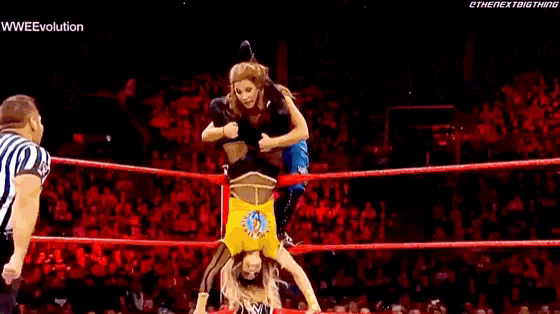 a woman is doing a flip in a wrestling ring while a referee watches .