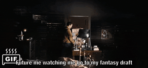 a man is looking out a window with the words `` future me watching me go to my fantasy draft '' below him .