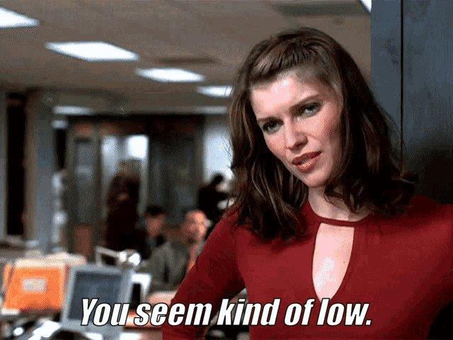 a woman in a red top is standing in an office and says you seem kind of low