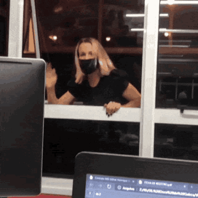 a woman wearing a face mask is looking out a window