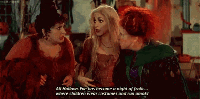 three women are standing next to each other and one of them is talking about halloween