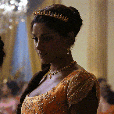 a woman wearing a tiara and a necklace looks at the camera