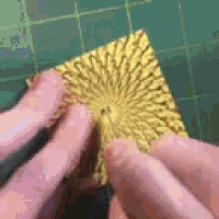 a person is holding a piece of yellow paper on a green mat .