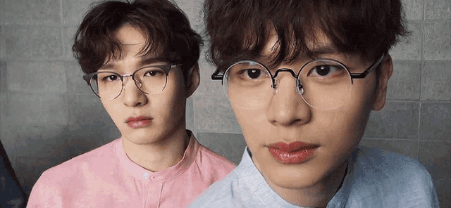 two young men wearing glasses and a pink shirt are standing next to each other