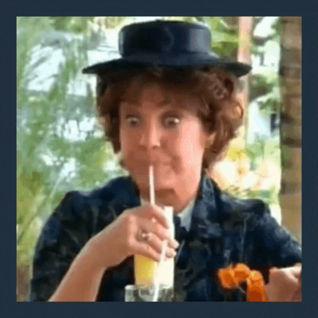 a woman in a hat is drinking through a straw from a glass