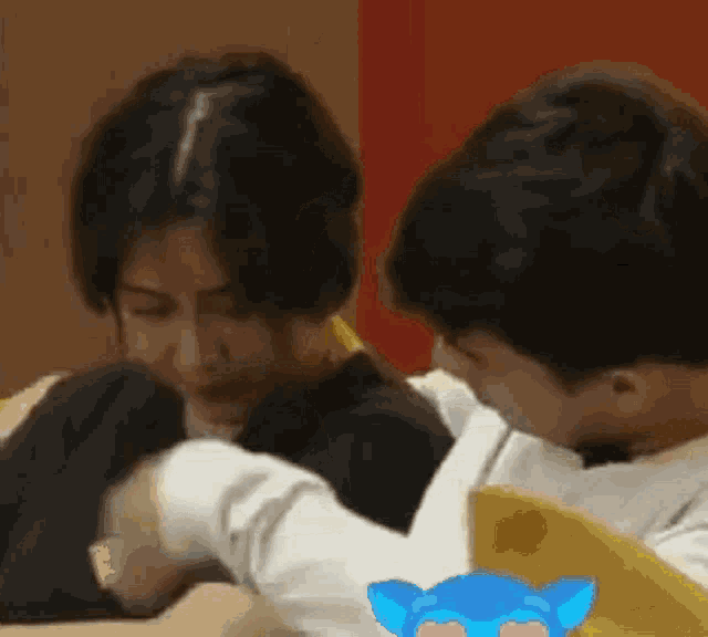 a man and a woman are sitting next to each other with a blue cat sticker on the back of the man 's shirt