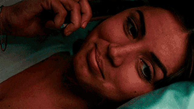 a woman laying on a bed talking on a phone