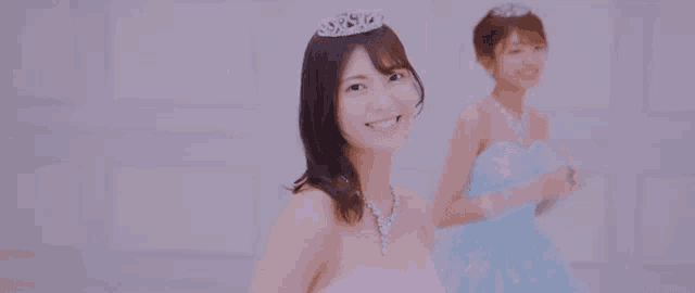 two women in wedding dresses are standing next to each other and smiling .