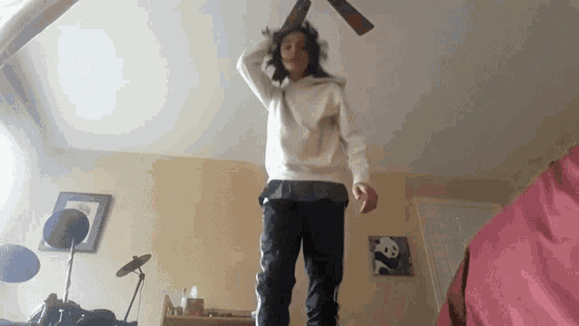 a woman in a white sweatshirt is standing in a room with a panda painting on the wall