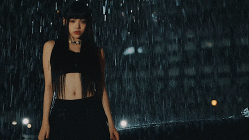 a woman stands in the rain in front of a sign that says love xxx