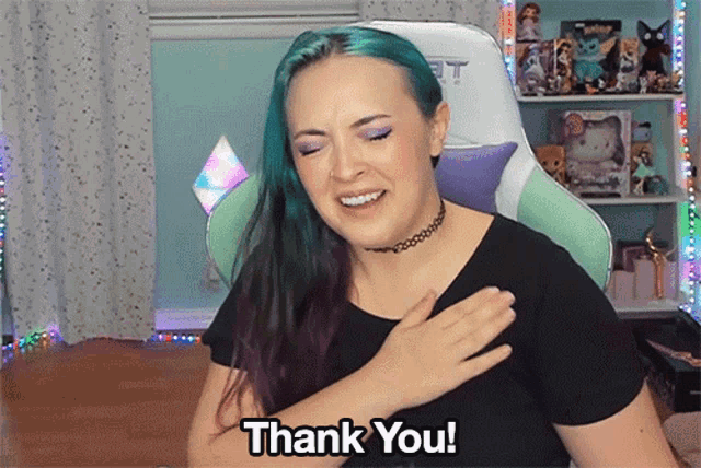 a woman with blue hair is saying thank you with her hands on her chest