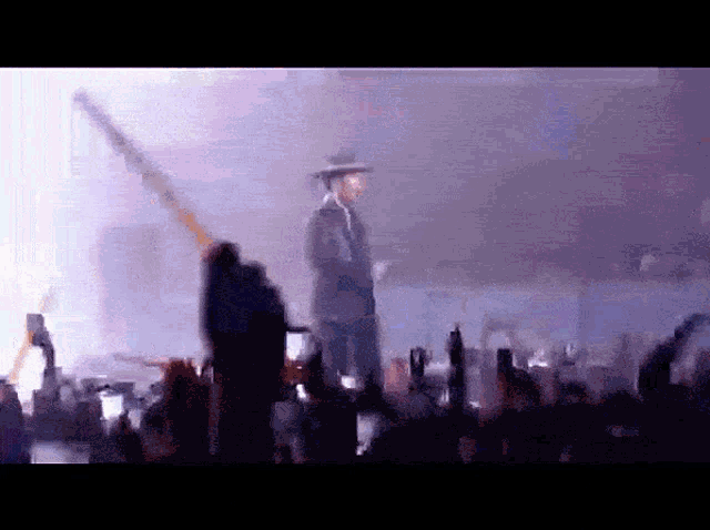 a man in a hat is standing in front of a crowd of people
