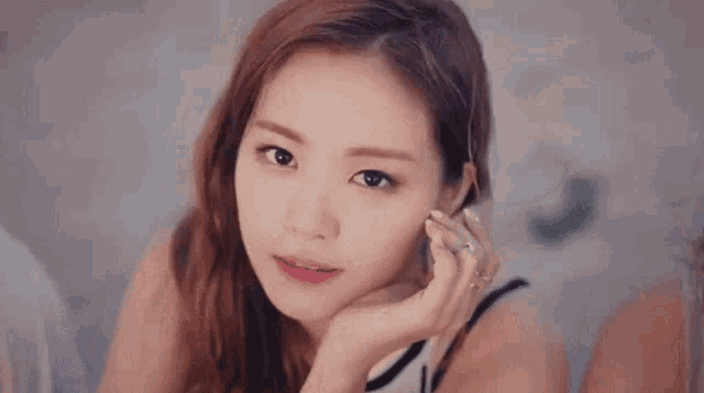 a close up of a young woman 's face with her hand on her chin .