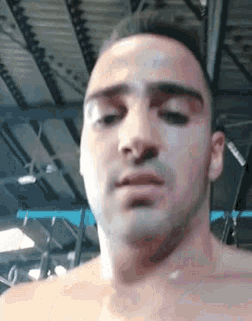 a shirtless man is standing in a gym and looking at the camera .
