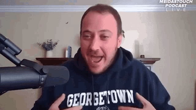a man wearing a hoodie that says georgetown stands in front of a microphone