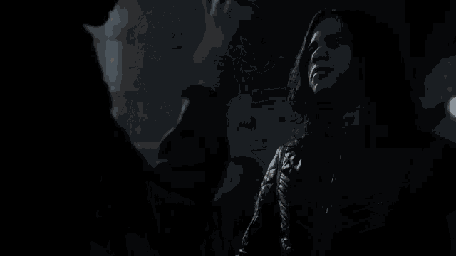 a man and a woman are standing next to each other in the dark .