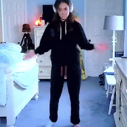 a woman wearing headphones stands in a bedroom