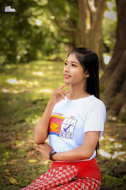 a woman wearing a ufc shirt sits in the grass