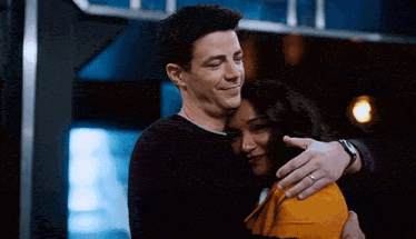 a man and a woman are hugging each other .