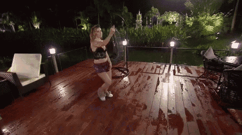 a woman is dancing on a wet deck at night .