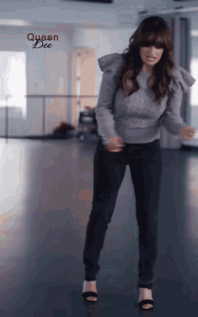 a woman in a purple sweater is dancing in a room with queen dee written in red