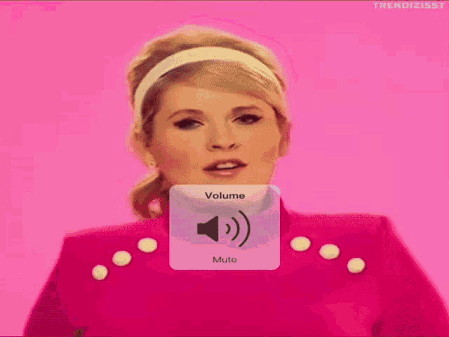 a woman in a pink dress is smiling with a volume mute button in front of her