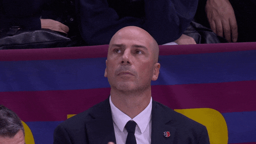 a bald man in a suit and tie with a badge that says fcb on it