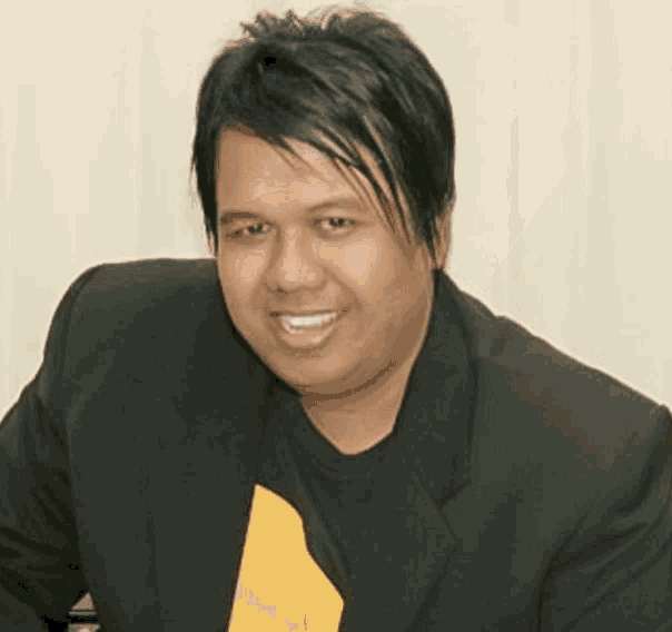 a man wearing a black jacket and a yellow shirt is smiling