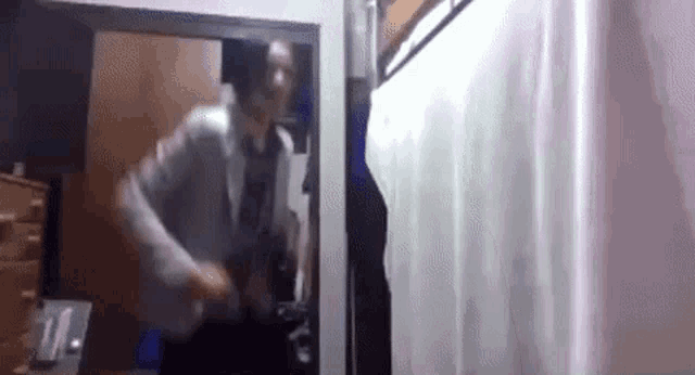 a man is standing in a room with a white curtain hanging on the wall .