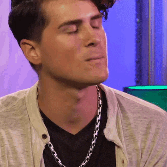 a man with his eyes closed wearing a silver chain