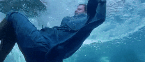 a man in a blue jacket is swimming in the water .