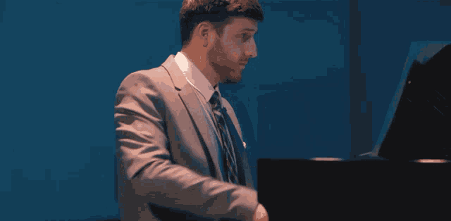a man in a suit and tie is playing the piano