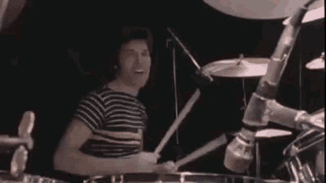 a person is playing drums on a stage with a microphone in the background .