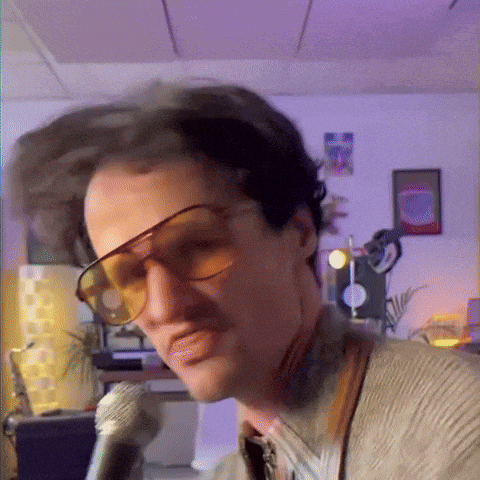 a man wearing sunglasses is singing into a microphone ..
