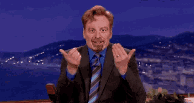 a man in a suit and tie making a gesture with his hands