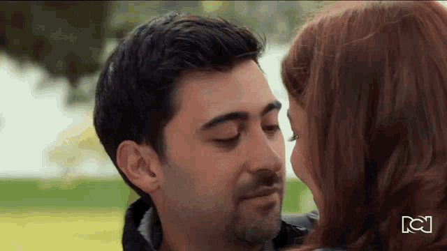 a close up of a man and woman kissing with the letters cc on the bottom