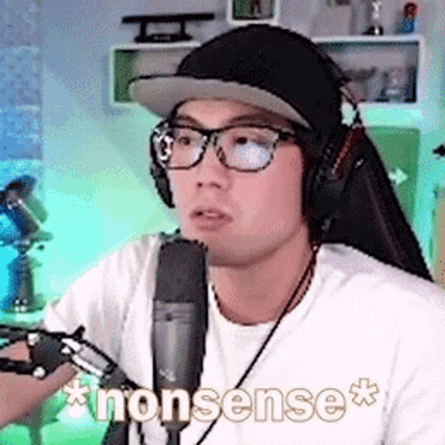 a man wearing glasses , headphones , and a hat is talking into a microphone .