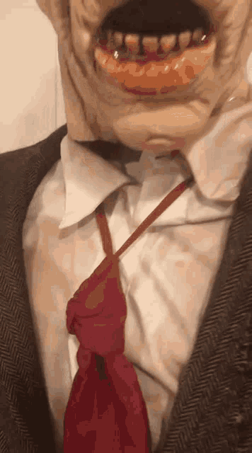a close up of a person wearing a suit and a red tie